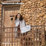 Frau trägt eine crèmefarbene Honeycomb-Fouta vor einer Natursteinwand