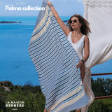 Frau hält eine blau gestreifte Palma-Fouta am Meer