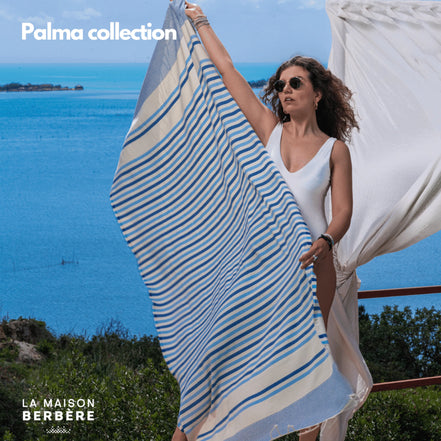 Frau hält eine blau gestreifte Palma-Fouta am Meer